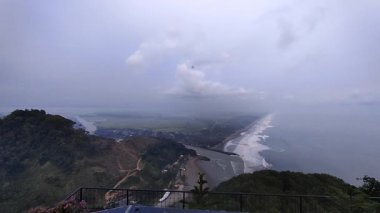 Puslu vadi manzarası, ormanlık tepeler, kıvrımlı nehir ve bulutlu gökyüzünün altındaki uzak yerleşim yerleri. Doğa, manzara veya seyahat temalı görsel içerik için ideal