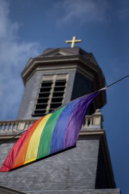 Hartebrugkerk kilise kulesiyle gökkuşağı bayrakları ve arka planda, Leiden, Hollanda.