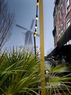 Green foliage and decorative lighting with De Walk windmill in the background, Leiden, Netherlands clipart