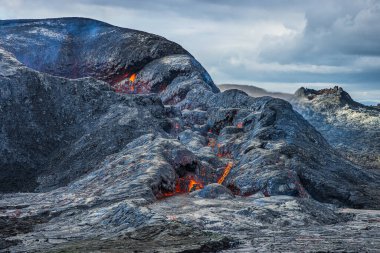 Krateri görüyorum. Soğutulmuş magmanın üzerinde lav bulunan bir kraterin yan açılışı. İzlanda 'daki volkanik manzara. Reykjanes yarımadası Bulutlu bir gökyüzü ile gün ışığında