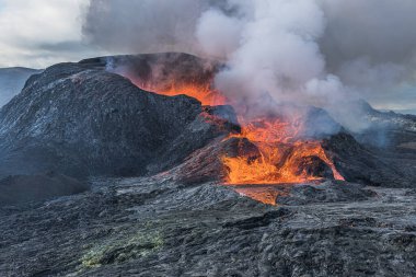 Yanardağ patlamadan sonra İzlanda 'da. Kraterin üzerindeki sıcak buhar bulutları açılıyor. Lav volkanik kraterden akıyor. Gündüz Reykjanes yarımadasında manzara. Önplanda koyu magma kayası