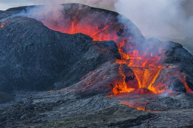 Yandan açılan kratere bak. İzlanda 'daki bir volkanın kraterinden lav akışı. GeoPark 'taki Reykjanes Yarımadası' nın manzarası. Gün boyunca kraterin üzerinde yoğun duman oluşumu