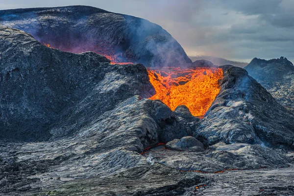 一座活火山的景象 冰岛雷克雅未斯半岛的火山口 黄昏时分 天空阴云密布 熔岩从火山口流出 火山口周围有较暗的岩浆 — 图库照片