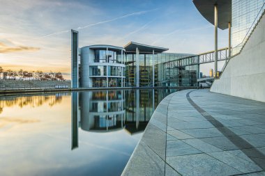 Berlin 'deki hükümet binası. Ön bina camlı. Almanya 'nın başkentinde akşam vakti yayılarak. Nehrin su yüzeyinde yansıma Spree