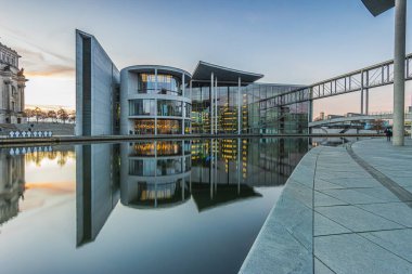 Akşam havası, gün batımında Berlin 'in hükümet bölgesinde Spree nehrinin su yüzeyine yansıyor. Almanya 'nın başkentinde Paul Loebe Haus hükümet binası.