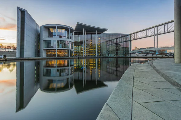 stock image Government building in Berlin at sunset. River Spree in the center of the capital of Germany. Glass facade building with illumination in the evening. reflection on the water surface