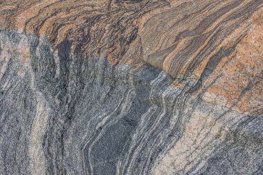 Granit taşın desenli arka planı. Çapraz bir rotada dalgalı çizgi çizimi ile renk kesintisi. Gri ve kahverengi desenli yüzey. Kaya içinde koyu renk