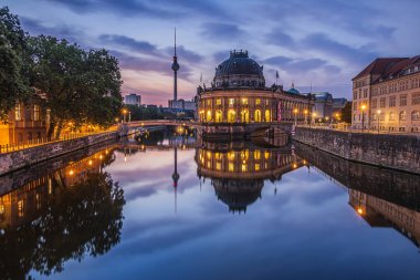 Sabahın mavi saatinde Müze Adası manzarası. Almanya 'nın başkentinde bir televizyon kulesi olan tarihi binalar. Aydınlatılmış binaların yansımaları