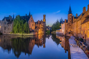 Eski Bruges kasabasında akşam atmosferi. Hanseatic şehrindeki Tespih İskelesi Kanalı 'nda. Kule çan kulesiyle tarihi binaların su yüzeyinde yansıma.