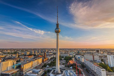 Gün batımında Berlin TV kulesi. Almanya 'nın başkenti Skyline. Alexanderplatz civarındaki şehir merkezinde akşamları binalar ve caddeler var. Arka planda Berlin 'in Kızıl Kasaba Salonu