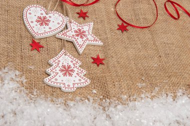 Çuval bezinin arka planında yapay kar ile ahşap Noel süslemeleri