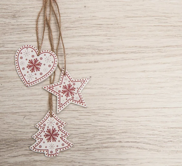 Tahta arka planda suni kar ile süslenmiş kırmızı ve beyaz ahşap Noel süslemeleri.