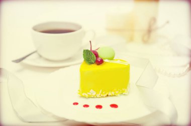 Retro color photograph with a cup of coffee and a heart-shaped cake on a light background