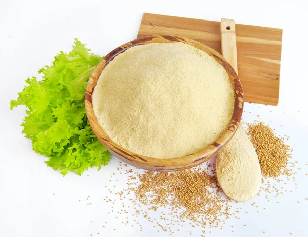 Stock image Mustard powder in a bowl, lettuce leaves and a wooden spoon on a white background