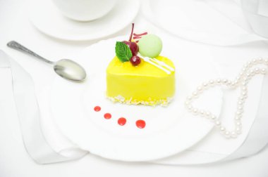 Sarı jöleli kek bir tabakta beyaz bir arka planda bir masada.