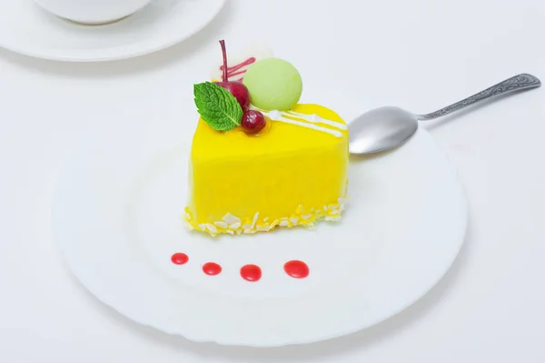 cake in yellow glaze on a plate on a table on a white background