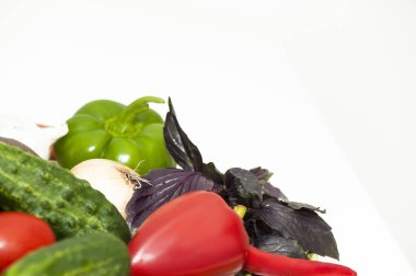 Farklı sebzeler, salatalıklar, domatesler, beyaz arka planda biberler.