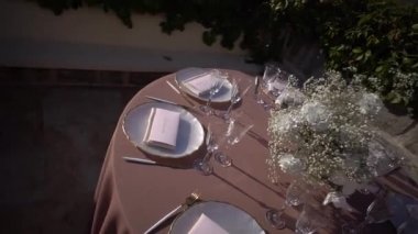 Çatal bıçak takımı, bardaklar ve bir buket beyaz çiçekli şenlik masası. Yüksek kaliteli FullHD görüntüler