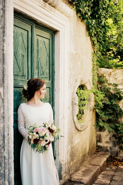 花园里一座古建筑的木门旁边 站着一个开着花的新娘 高质量的照片 — 图库照片
