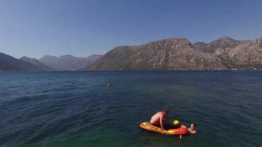 Turistler denizde yüzer ve kıyıya yakın şişme daireler çizerler. Yüksek kalite 4k görüntü