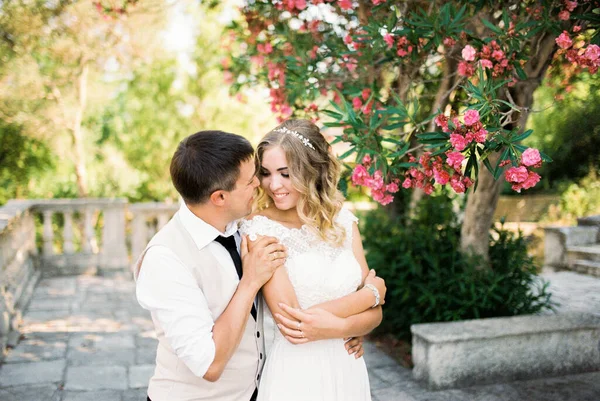 Groom Étreint Mariée Par Derrière Par Les Épaules Sous Une — Photo