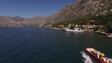 Motorlu tekne, demirli yatlarla dağlık sahil boyunca yelken açıyor. Yüksek kalite 4k görüntü