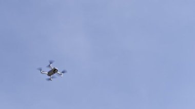 Four-engine drone soars in the air against a blue sky. High quality FullHD footage