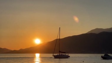 Moored yachts rock on the waves against the backdrop of mountains at sunset. High quality 4k footage