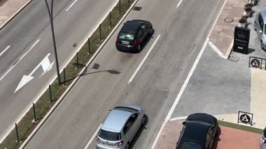 Cars drive along the highway past modern buildings among green trees. Budva, Montenegro. High quality 4k footage