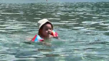 Little girl in inflatable armlets swims in the sea. High quality 4k footage