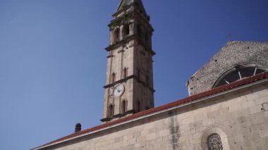 High bell tower of the church of St. Nicholas against the blue sky. Perast. High quality FullHD footage