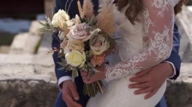 Bride sits on the lap of groom with a bouquet of flowers in her hands. High quality FullHD footage