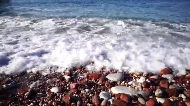 Beyaz köpüklü fırtına dalgaları çakıl taşı plajında yuvarlanıyor. Yüksek kaliteli FullHD görüntüler
