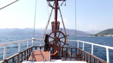 Helm of a sailboat floating on the sea against the backdrop of mountains. High quality 4k footage