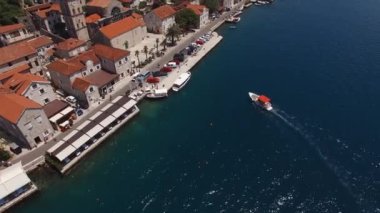 Excursion boat sails up to the pier with a parking lot. Perast, Montenegro. High quality 4k footage