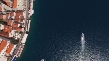 Motorlu yat Perast kıyısından demirli yolcu gemileriyle geçiyor. Drone. Yüksek kalite 4k görüntü