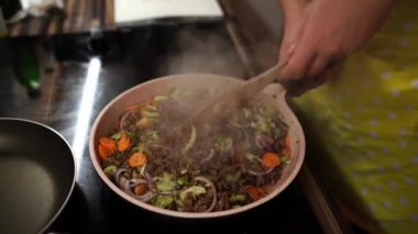 Chef mixes minced meat with vegetables in a frying pan with a spatula. High quality 4k footage