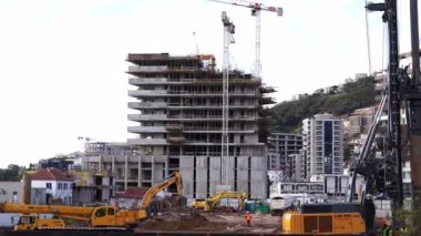 Excavators and cranes work at the construction site of a multistory building. High quality 4k footage