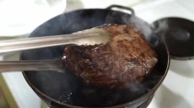 Cook takes the roast beef out of the pan with tongs and puts it on a plate. High quality 4k footage