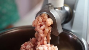 Pink meat is twisted in a meat grinder and falls into a bowl. High quality 4k footage