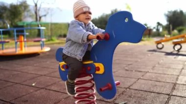 Little girl swings on a spring swing in the playground. High quality 4k footage