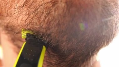 Man shaves his chin with a trimmer. Portrait. High quality 4k footage