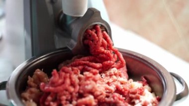 Red and pink minced meat comes out of the electric meat grinder into the pan. High quality 4k footage