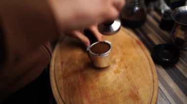 Man presses ground coffee in a portafilter on a cutting board with a tamper. High quality 4k footage