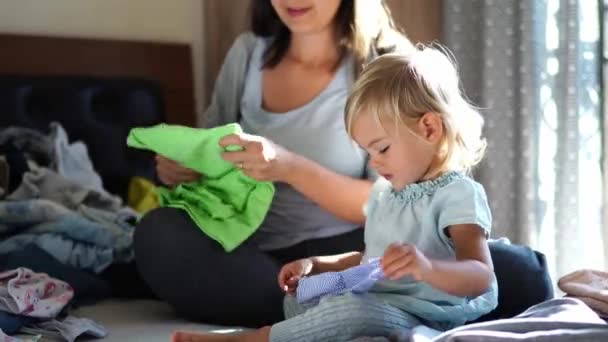 Küçük Kız Annesinin Yanında Oturup Temiz Çarşafları Sıralarken Koruyucu Bir — Stok video