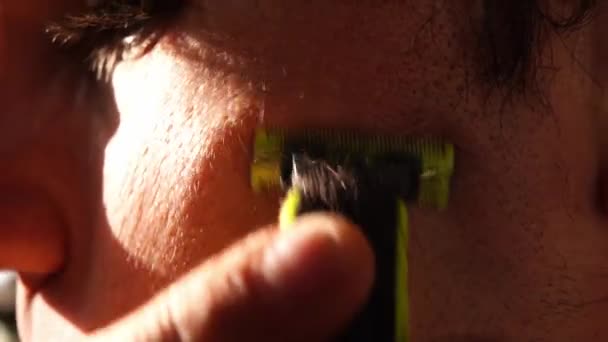 Jongeman Scheert Zijn Bakkebaarden Wangen Met Een Elektrische Trimmer Hoge — Stockvideo
