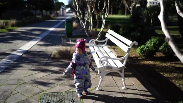 Маленькая Девочка Рюкзаком Гуляет Возле Скамейки Парке Высококачественные Кадры — стоковое видео