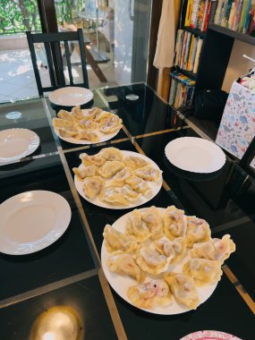 Row of plates with dumplings stand on a table in the kitchen. High quality photo