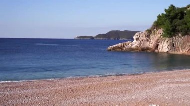 Pebble beach near stone cliff with green trees. High quality FullHD footage