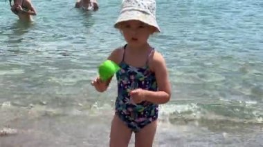 Little girl holding a plastic bucket on the beach. High quality 4k footage